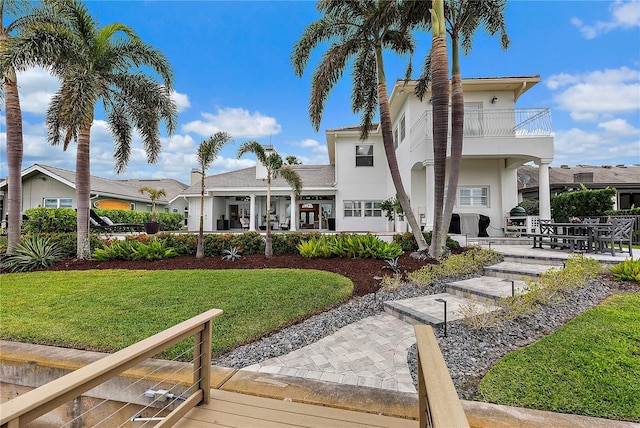 exterior space with a balcony and a front yard