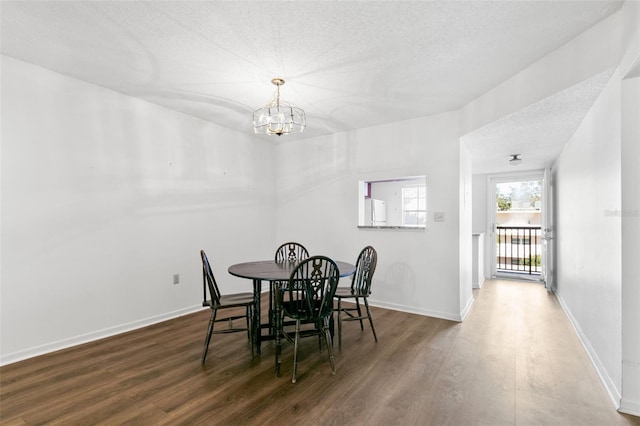 dining area featuring dark hardwood / wood-style flooring, a textured ceiling, and a notable chandelier