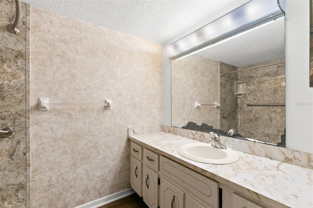 bathroom with vanity, hardwood / wood-style floors, a textured ceiling, and tiled shower