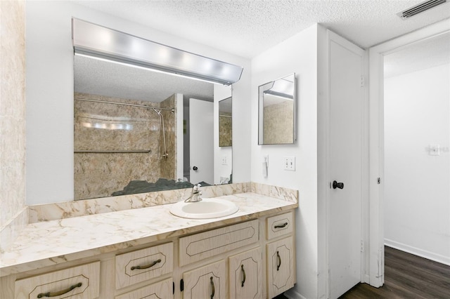 bathroom with a shower, a textured ceiling, vanity, and hardwood / wood-style flooring