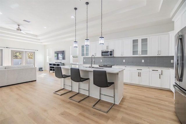 kitchen with white cabinetry, sink, a kitchen island with sink, and appliances with stainless steel finishes