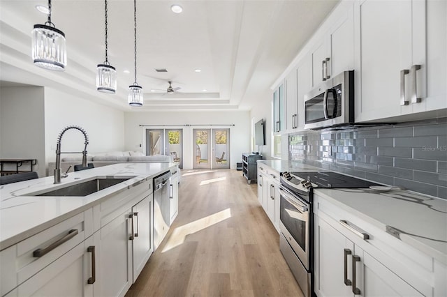 kitchen with white cabinetry, sink, french doors, a tray ceiling, and appliances with stainless steel finishes