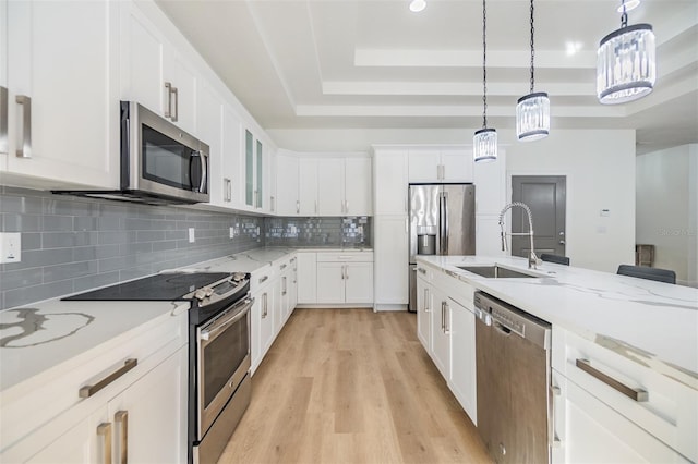 kitchen with light stone counters, stainless steel appliances, sink, pendant lighting, and white cabinets