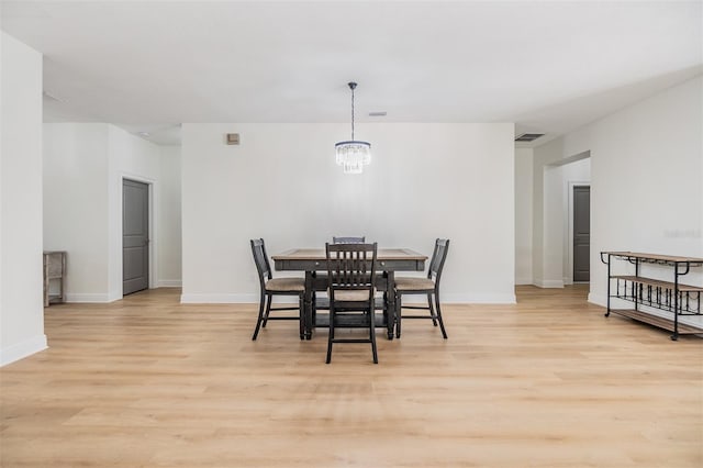 dining area with light hardwood / wood-style floors and an inviting chandelier