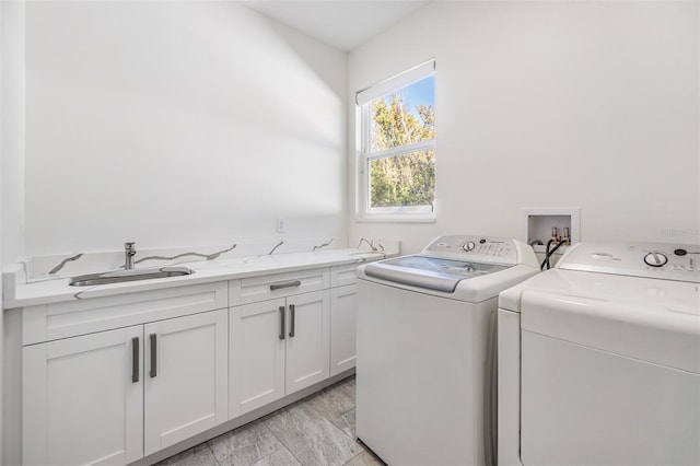 laundry area featuring cabinets, separate washer and dryer, sink, and light hardwood / wood-style flooring