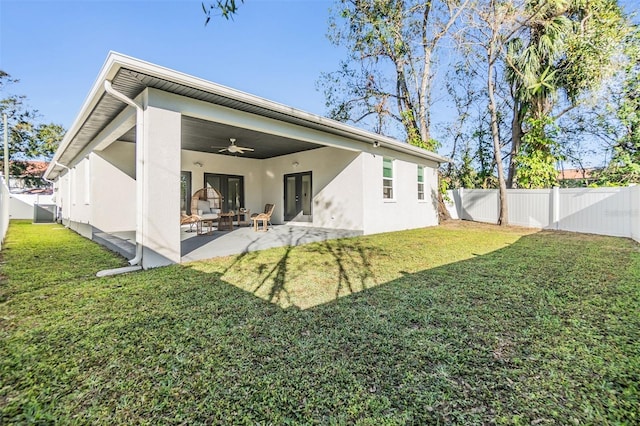 back of house featuring ceiling fan, a patio area, and a lawn