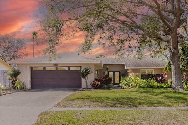 view of front facade featuring driveway, a front lawn, an attached garage, and stucco siding