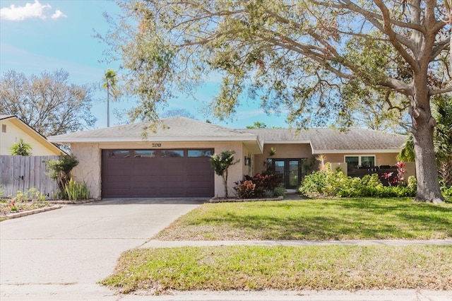 ranch-style home with a front lawn, an attached garage, fence, and stucco siding