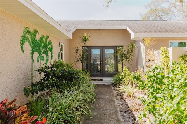 property entrance with french doors, roof with shingles, and stucco siding