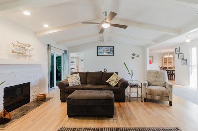 living area with vaulted ceiling with beams, light wood finished floors, recessed lighting, ceiling fan, and a stone fireplace