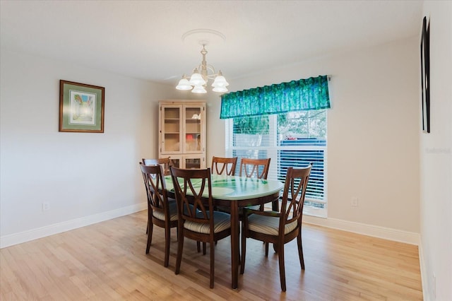 dining area with a chandelier, light wood finished floors, and baseboards