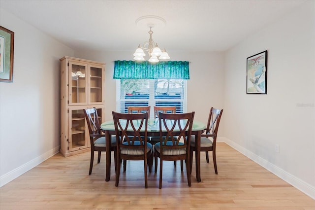 dining space with a chandelier, light wood-type flooring, and baseboards