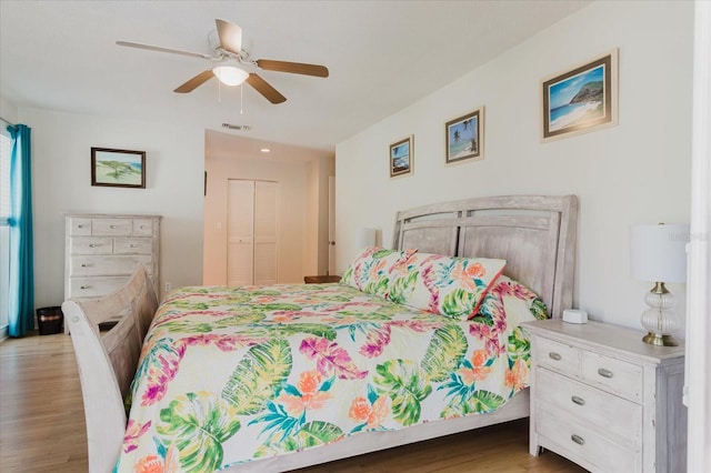 bedroom featuring light wood-style flooring, a closet, visible vents, and a ceiling fan