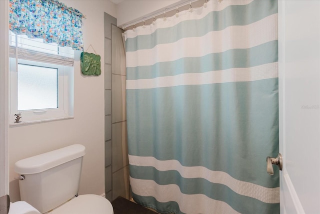 bathroom featuring toilet and curtained shower