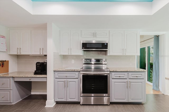 kitchen featuring light stone countertops, tasteful backsplash, appliances with stainless steel finishes, and white cabinets