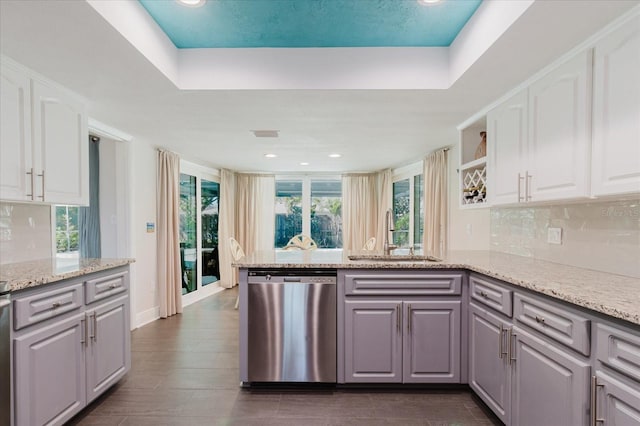 kitchen featuring white cabinets, dishwasher, backsplash, a peninsula, and a sink