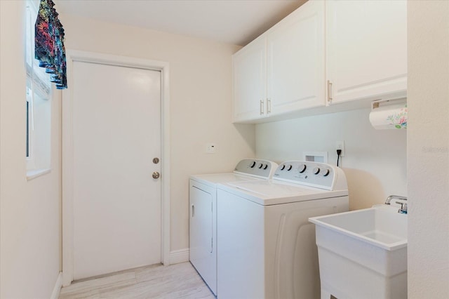 laundry room featuring a sink, baseboards, light wood-style floors, cabinet space, and washer and clothes dryer