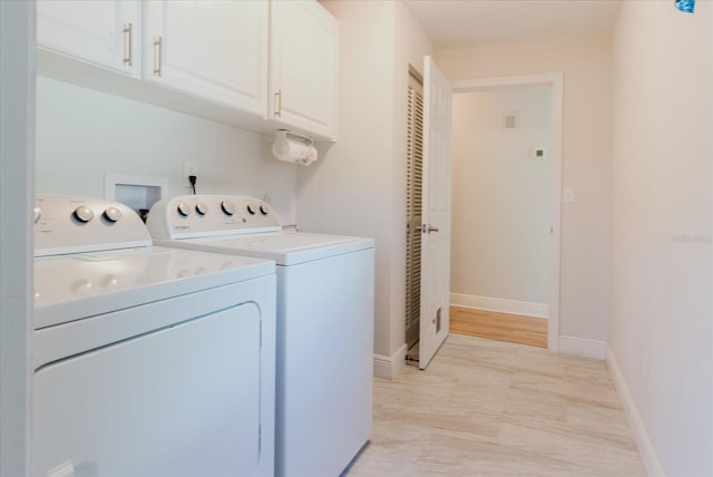 clothes washing area with washing machine and dryer, cabinet space, and baseboards