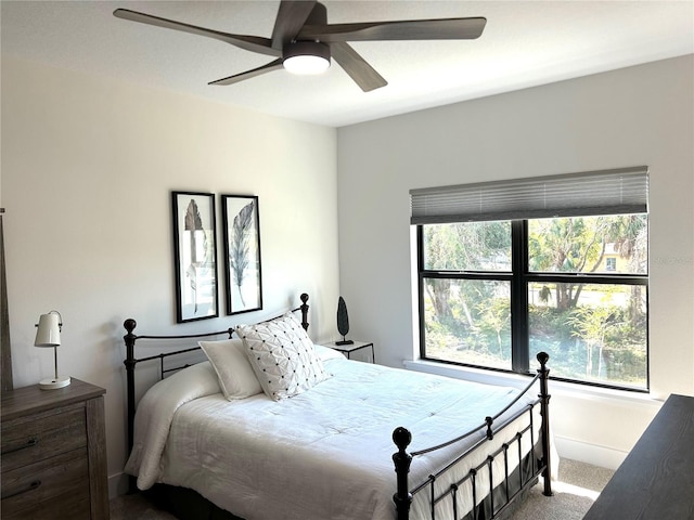 carpeted bedroom with multiple windows, baseboards, and a ceiling fan