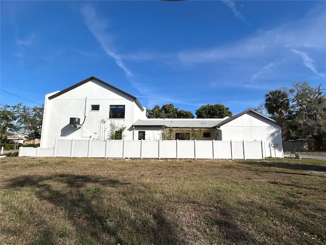 exterior space with fence, a lawn, and stucco siding