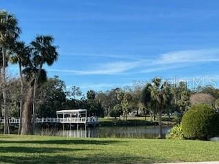 surrounding community with a water view and a yard