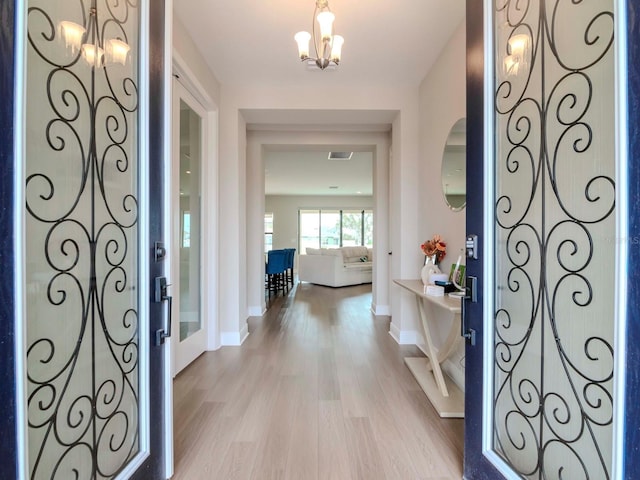 foyer with light hardwood / wood-style flooring and an inviting chandelier