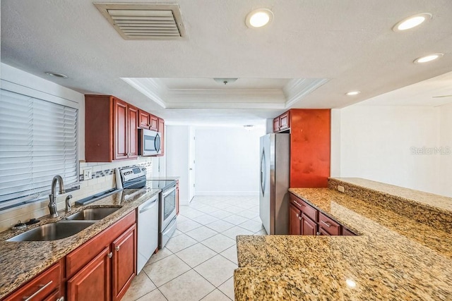 kitchen with ornamental molding, sink, appliances with stainless steel finishes, and a tray ceiling