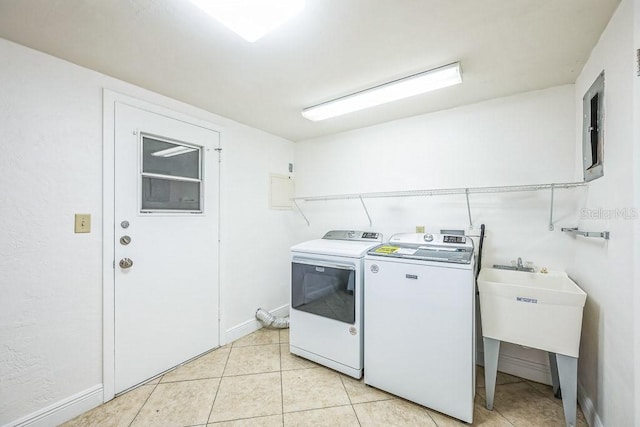 clothes washing area with washing machine and clothes dryer, sink, and light tile patterned floors