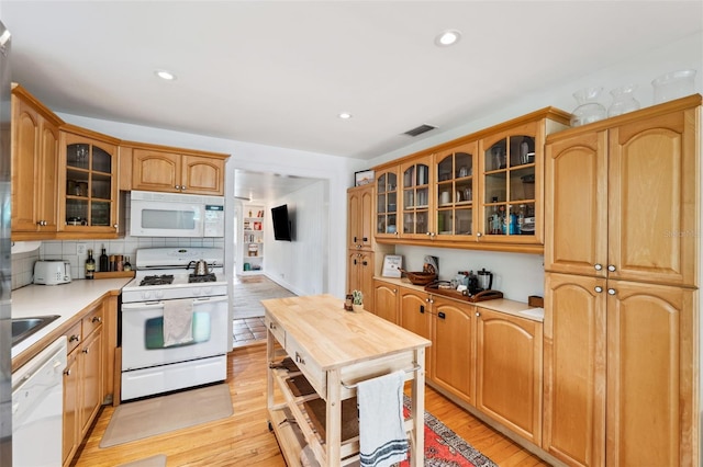 kitchen featuring white appliances, light hardwood / wood-style flooring, and backsplash