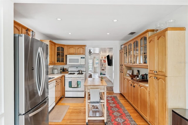 kitchen featuring decorative backsplash, white appliances, and light hardwood / wood-style floors