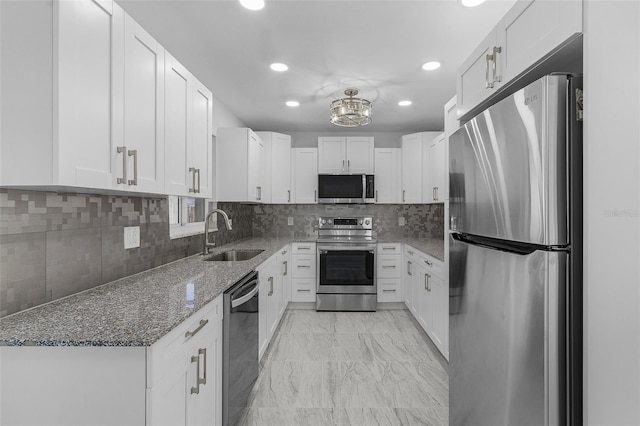 kitchen featuring stone counters, stainless steel appliances, white cabinetry, and sink