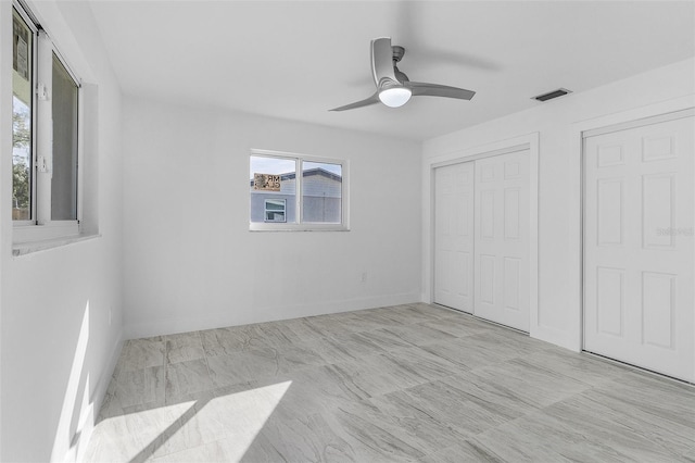 unfurnished bedroom with ceiling fan and two closets