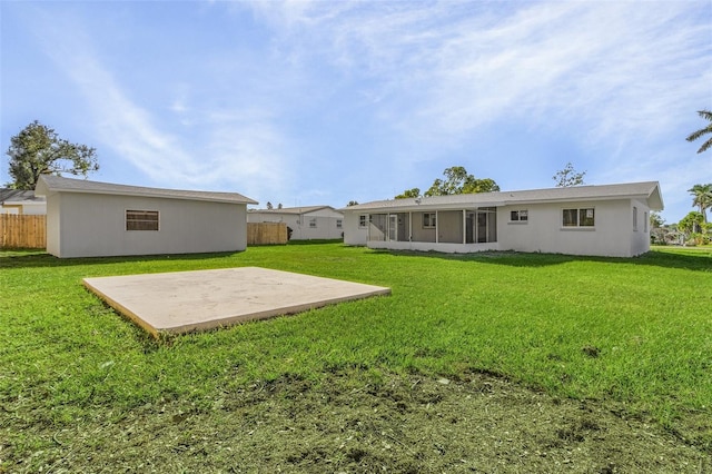 rear view of house featuring a sunroom, a patio area, and a yard