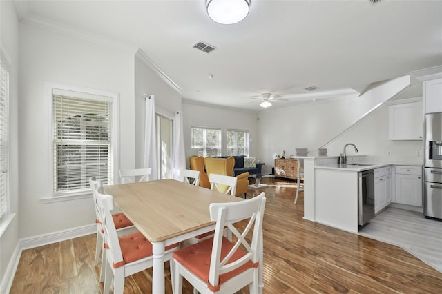 dining space with light hardwood / wood-style flooring, ceiling fan, ornamental molding, and sink