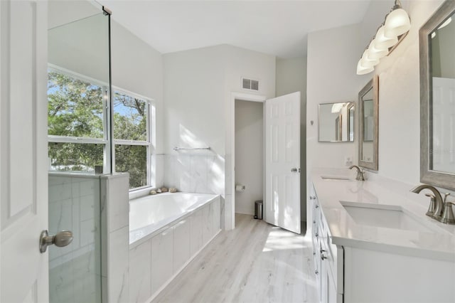 full bathroom featuring plus walk in shower, wood-type flooring, vanity, and toilet