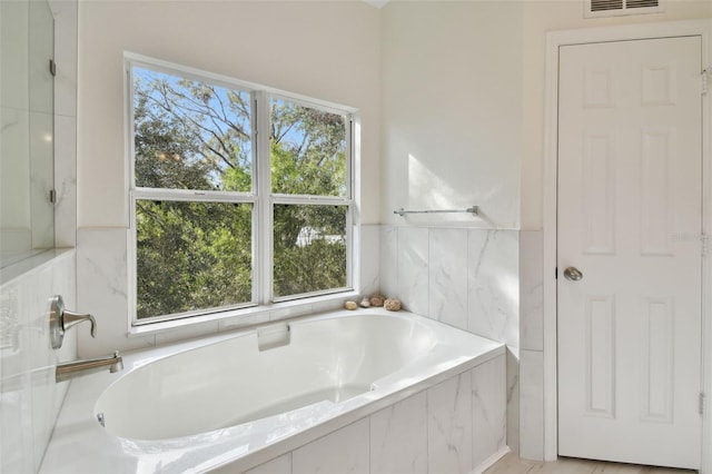 bathroom featuring tiled bath and plenty of natural light