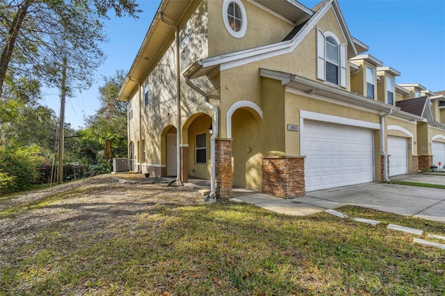 view of front of property with a garage, a front yard, and central air condition unit