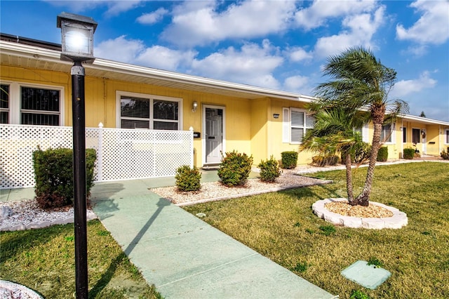 ranch-style home with a front yard and stucco siding