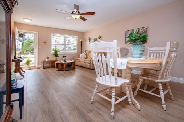 dining room featuring light wood finished floors, ceiling fan, and baseboards