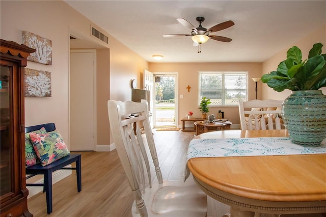 dining room with baseboards, visible vents, ceiling fan, and light wood finished floors