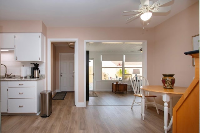 dining room with light wood-type flooring, a ceiling fan, and baseboards