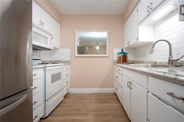 kitchen with white appliances, decorative backsplash, light wood-style floors, white cabinetry, and a sink