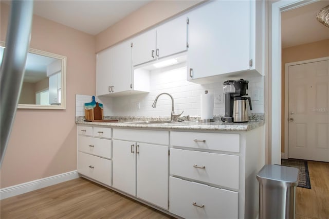 kitchen featuring a sink, light wood-style flooring, and white cabinets