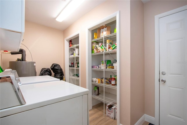 laundry room featuring light wood-style floors, washing machine and dryer, water heater, and cabinet space