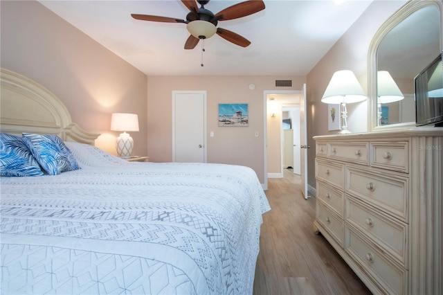 bedroom featuring visible vents, ceiling fan, baseboards, and wood finished floors