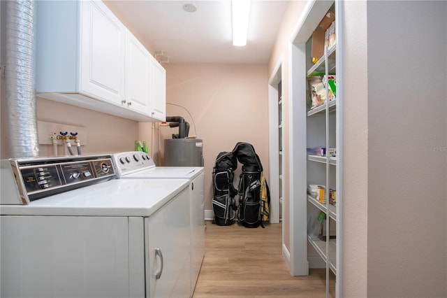 clothes washing area with light wood-style flooring, baseboards, water heater, washer and dryer, and cabinet space