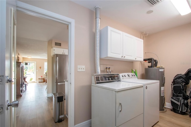 laundry room with washing machine and dryer, light wood-style flooring, visible vents, water heater, and cabinet space