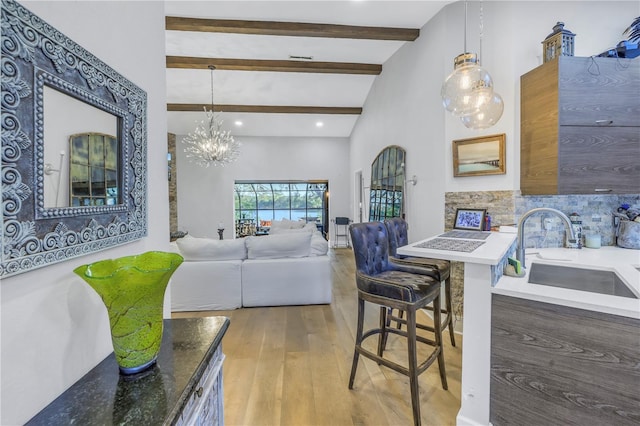 living room with an inviting chandelier, sink, light hardwood / wood-style flooring, a towering ceiling, and beamed ceiling