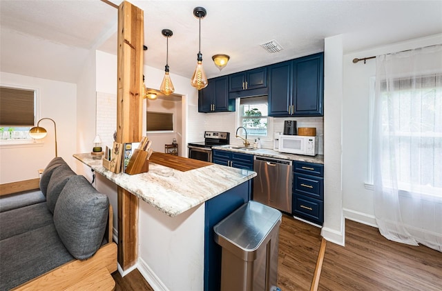 kitchen with a kitchen breakfast bar, backsplash, stainless steel appliances, blue cabinets, and pendant lighting