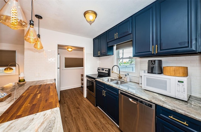 kitchen with stainless steel appliances, blue cabinets, sink, decorative light fixtures, and butcher block counters